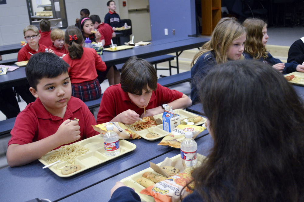 Jude Cobler, left, eats lunch with classmates at All Saints Catholic School in Far North Dallas. Photo/Christina Ulsh