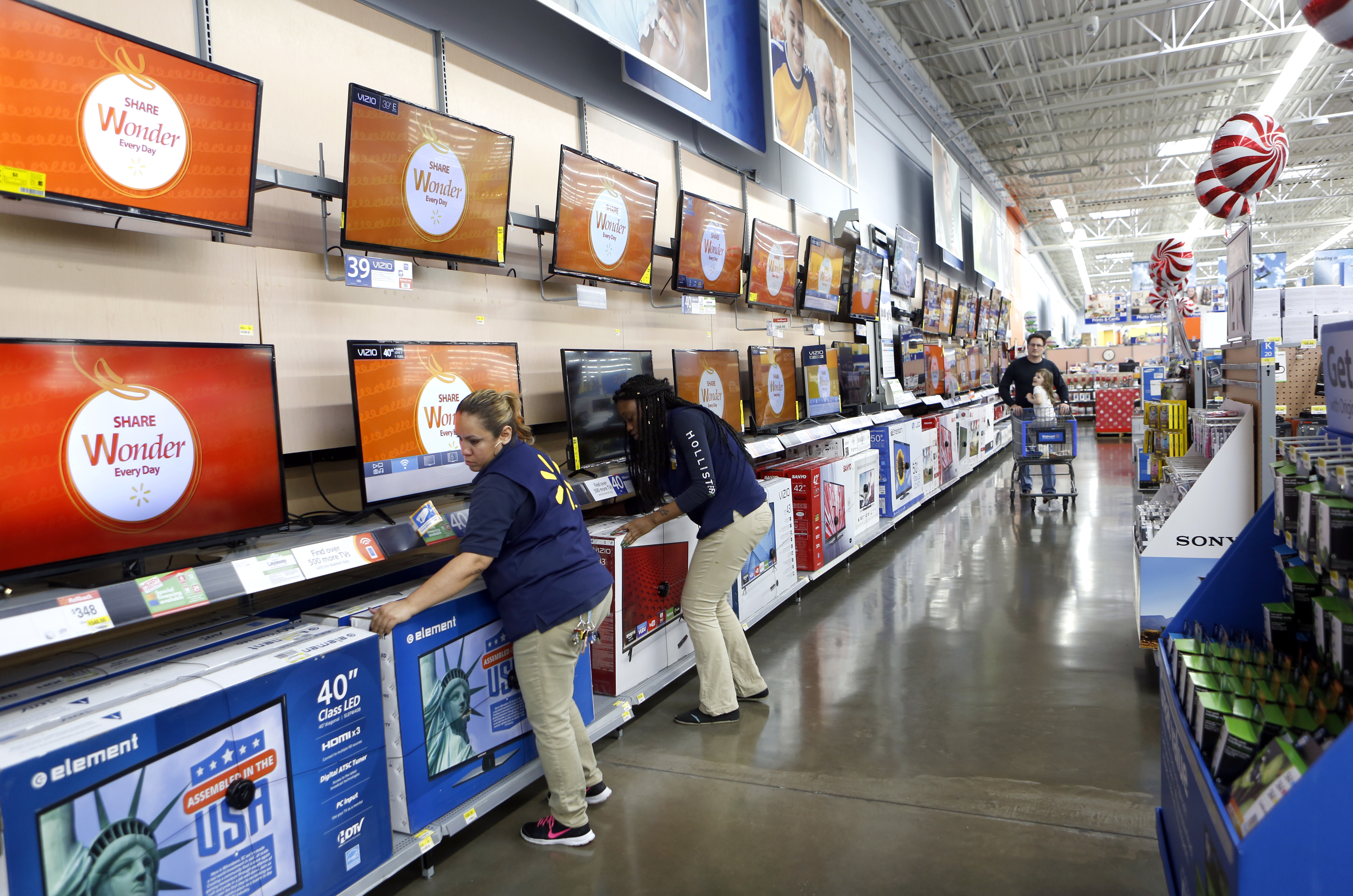 Employees Leslie Luna (left) and Kenya Phelps (right) straighten the TV display at Walmart in Dallas. Photographed on Monday, November 16, 2015. Photo/Lara Solt