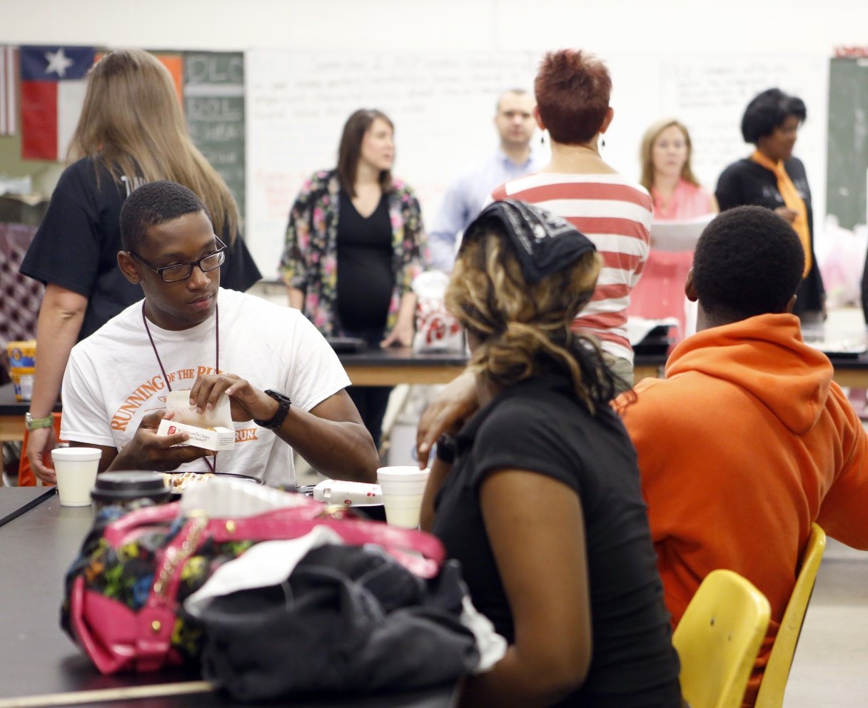 Desmond Davis, far left, and other students considered homeless or transitional, eat food provided to them by volunteers from the Church of the Incarnation at drop-in center at North Dallas High School. Photo/Lara Solt