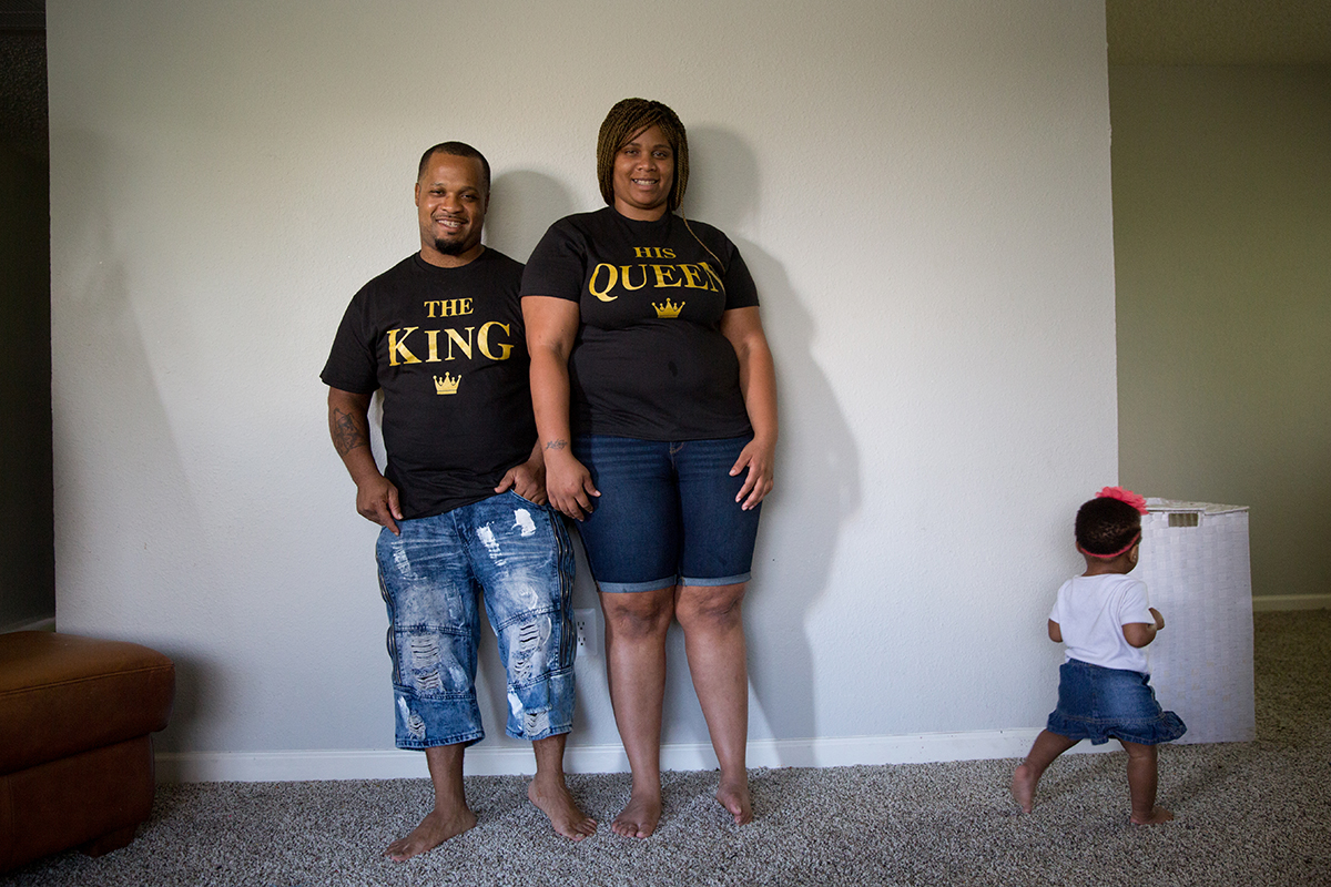 Stanley Walington and Lynette Sherman stand for a portrait in their Fort Worth apartment, with their daughter Honesty, 1, in the frame. / Credit: Allison V. Smith